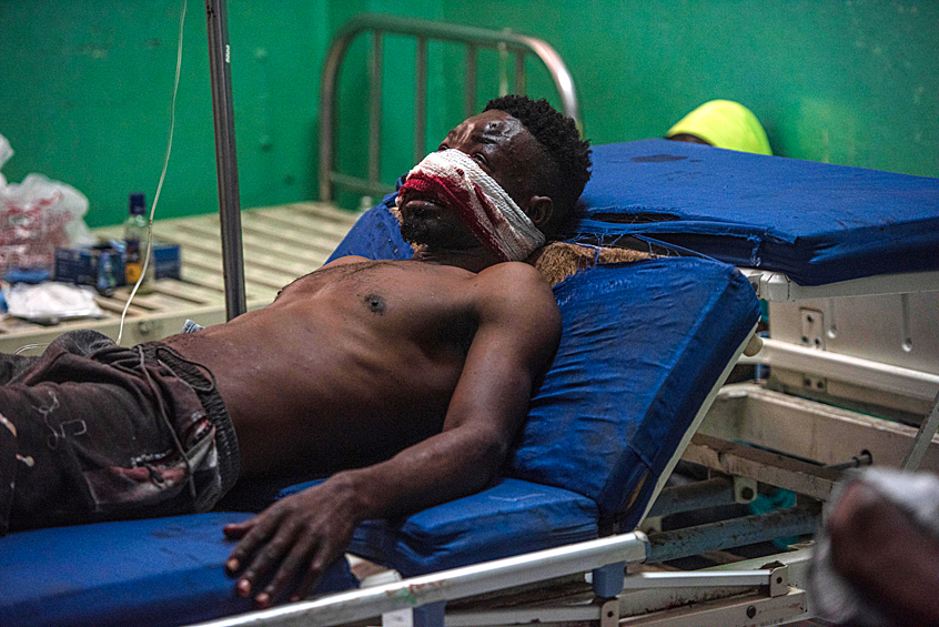 Раненый мужчина ожидает лечения в медицинском центре в Порт-о-Пренсе